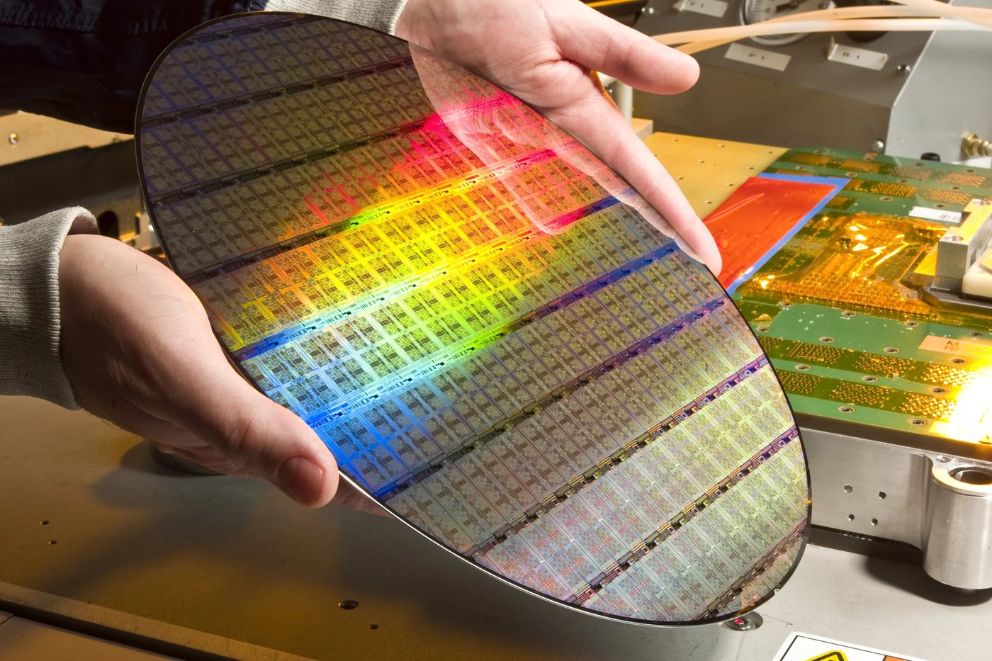 Silicon wafer in gloved hands, refracting rainbow light